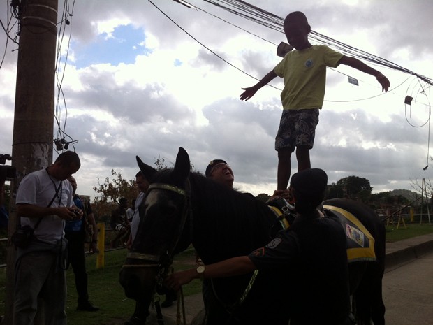O menino Andrey Felipe Pinheiro, de 8 anos, fica em pé no cavalo da PM, na Favela da Cachoeirinha. O subcomandante do RPMont, tenente coronel Edson Muniz, explica que o cavalo tem a função de integrar os moradores aos policiais militares. (Foto: Tássia Thum/G1)