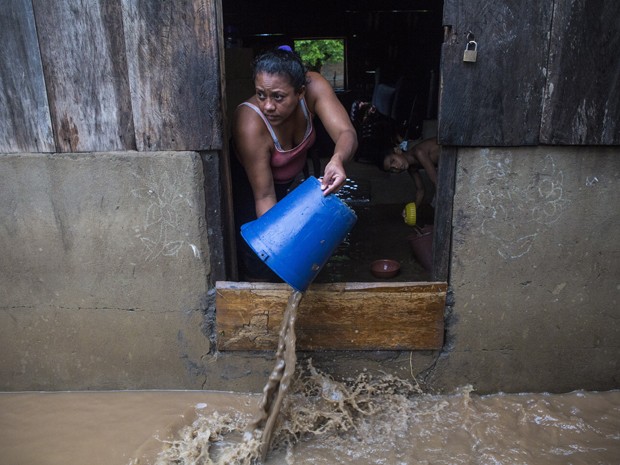 Com balde, mulher retira água de dentro de casa após a cheia do rio Ochomogo, em Barraza, a cerca de 30 km da cidade de Rivas, na Nicarágua  (Foto: AFP Photo/Inti Ocon)