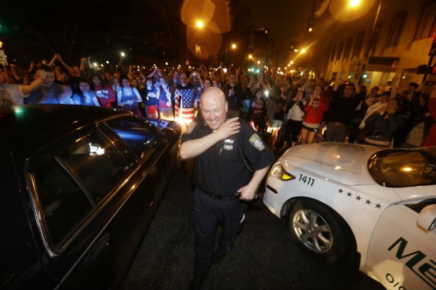Policial diante da multidão que celebra, na noite desta sexta-feira, o fim da operação para prender os suspeitos do atentando na Maratona de Boston (Foto: Julio Cortez/AP)