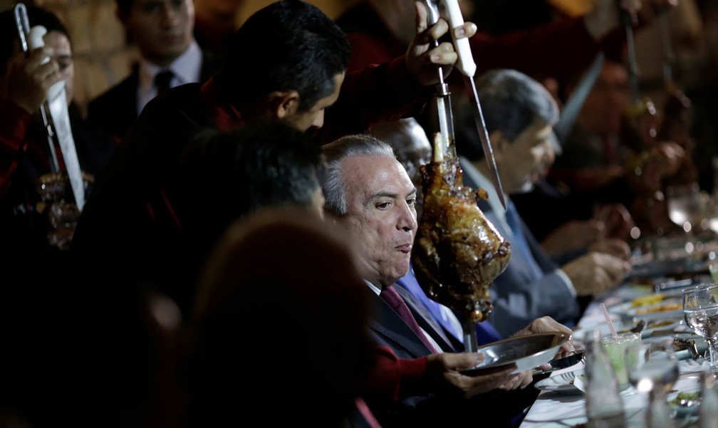 O presidente Michel Temer come carne de churrasco acompanhado de embaixadores de países que importam carne brasileira em uma churrascaria de Brasília, na noite de domingo (19) (Foto: Ueslei Marcelino/Reuters)
