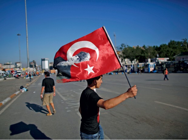 REVOLTA Manifestante  em Istambul empunha bandeira turca com a face de Kemal Atatürk. Em defesa de um regime laico (Foto: Stoyan Nenov/Reuters)