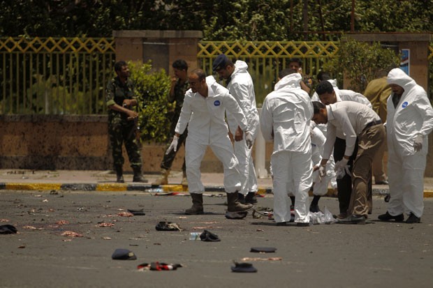 Restos humanos são vistos ao redor de policiais forenses na via de Sanaa, capital iemenita (Foto: Khaled Abdullah/Reuters)