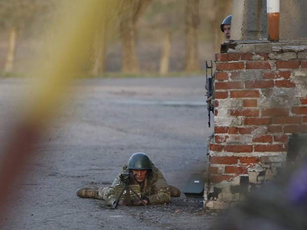 Um soldado ucraniano aponta arma para manifestantes pró-Rússia em frente a uma base aérea em Kramatorsk (Foto: Reuters/Marko Djurica)