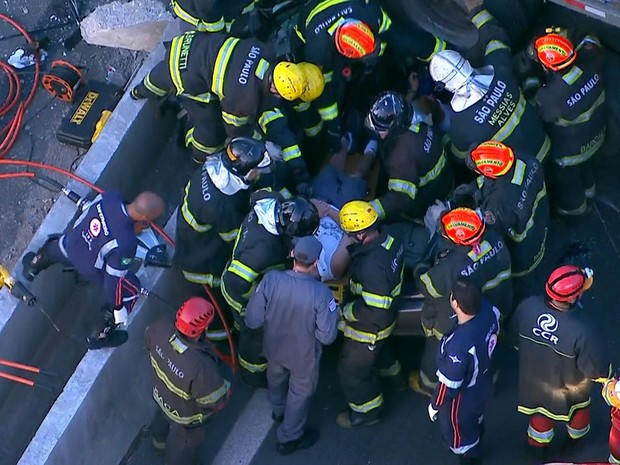 Ferido é retirado por bombeiros de veículo atingido por carreta na Dutra em Guarulhos (Foto: Reprodução/TV Globo)