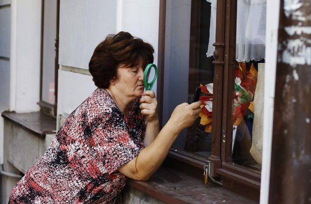 Mulher usa lupa para conseguir escrever e enivar mensagem em celular (Foto: Marko Djurica/Reuters)