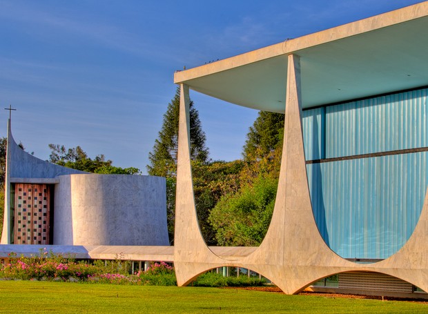 As pilastras tão características do desenho de Niemeyer se transformaram na identidade do Distrito Federal. Ao lado, a capela dedicada à Nossa Senhora da Conceição tem vitrais de Athos Bulcão (Foto: Ichiro Guerra/Reprodução)