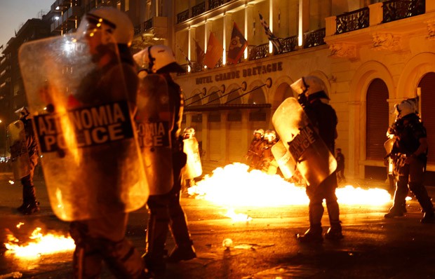 Policiais passam por chamas durante confronto com um pequeno grupo de manifestantes anti- austeridade em frente ao parlamento em Atenas, na Grécia  (Foto: Yannis Behrakis/Reuters)