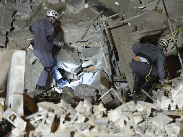 Homens do Corpo de Bombeiros buscam por vítimas em meio aos escombros de prédio em obras que desabou em Guarulhos, SP. (Foto: José Patrício/ Estadão Conteúdo)