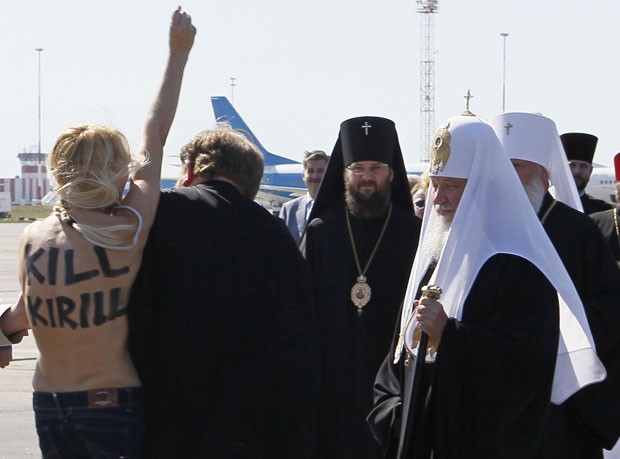 Com os seios à mostra e a frase 'Matem Kirill' pintada nas costas, ao menos uma das feministas conseguiu chegar bem perto do religioso no aeroporto de Borispol, aparentemente para tentar agredi-lo. (Foto: Gleb Garanich/Reuters)