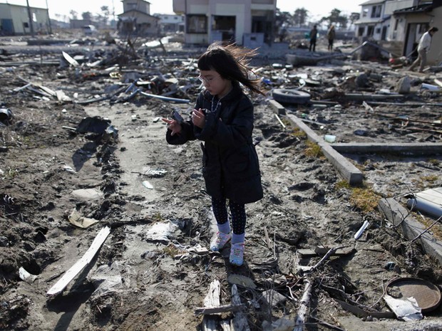 Criança visita local onde ficava sua casa, Higashimatsushima, antes do tsunami (Foto: Reuters)