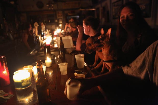 Moradores locais bebem à luz de velas no bar do JJ durante o apagão ocasionado pela passagem do furacão Isaac (Foto: John Moore/Getty Images/AFP)