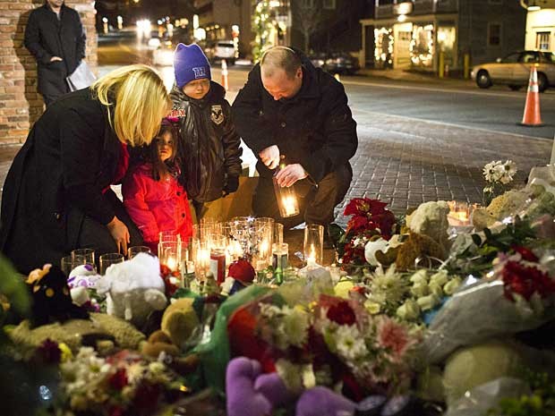 Muito moradores, como o casal Steven e Norma Macchia, e seus filhos de 7 e 3 anos, acenderam velas e rezaram na noite deste sábado (22) em um memorial para as vítimas do massacre. (Foto: Andrew Burton / Reuters)