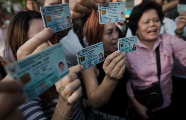 Tailandeses que não conseguiram votar mostram identidades e gritam para policiais em Bangcoc, neste domingo (2) (Foto: Nicolas Asfouri/AFP)