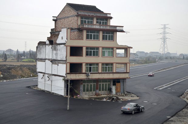 No ano passado, uma estrada foi construída ao redor de um pequeno prédio em Wenling, na província de Zhejiang, na China, depois que os donos se recusaram a fazer um acordo. Após o caso se tornar notícia internacional, o prédio acabou demolido (Foto: China Daily/Reuters)