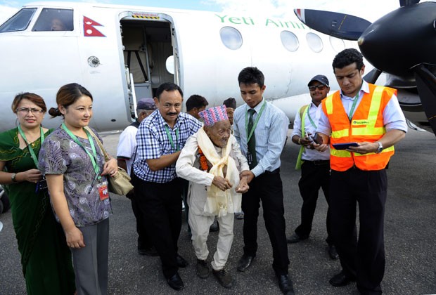 Bote Rai recebe ajuda para sair de avião após realizar o sonho de voar pela primeira vez (Foto: Prakash Mathema/AFP)
