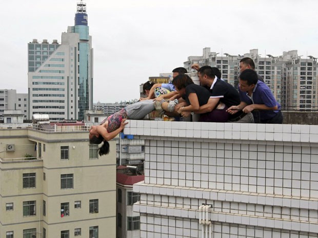 Familiares se aproximaram e tentaram retirá-la do topo do edifício (Foto: Reuters)