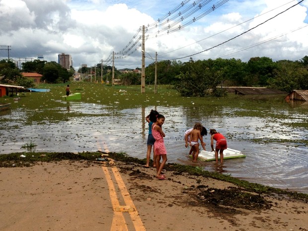 Crianças brincam na beira de rua tomada por água. (Foto: Ana Luiza Moreira/G1)