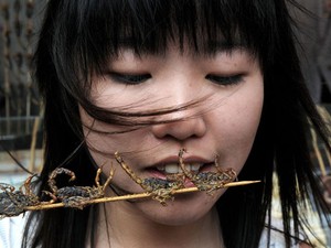 Chinesa come espetinho de escorpião em rua de Pequim, na China, em julho de 2008 (Foto: Mark Ralston/AFP)