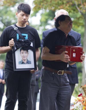 Di Rang Lin,, pais do estudante Jun Lin, segura urna com cinzas do filho durante funeral em Montreal, nesta quinta (26)  (Foto: Christinne Muschi / Reuters)