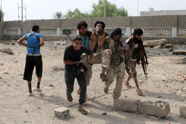 Combatentes leais ao governo do Iêmen carregam ferido durante combates em Aden nesta quinta-feira (16) (Foto: Saleh Al-Obeidi/AFP)