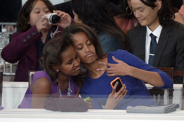 As filhas do casal Obama, Sasha (esq.) e Malia, fazem pose de 'rappers' para foto com o celular durante desfile celebrando a posse do pai.  (Foto: Joe Klamar/AFP)