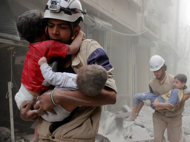 Membros da Defesa Civil resgatam crianças após ataque aéreo na cidade síria de Aleppo (Foto: Sultan Kitaz/Reuters)