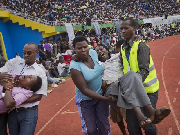 Mulheres passam mal durante uma cerimônia pública para marcar o 20 º aniversário do genocídio de Ruanda, no estádio Amahoro  (Foto: Ben Curtis/AP)