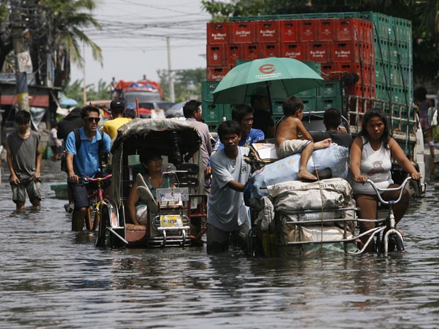 Moradores de Malabon, ao norte de Manila, nas Filipinas, tiveram que enfrentar ruas alagadas nesta segunda-feira (18) por conta da passagem do tufão "Butchoy" pela região. (Foto: REUTERS/Romeo Ranoco)
