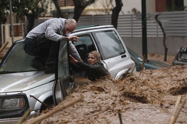 Morador de Chalandri socorre a motorista ilhada em seu carro (Foto: John Kolesidis/Reuters)