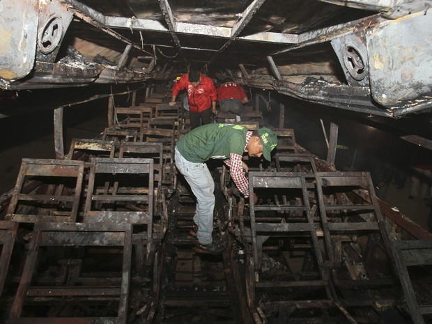 Equipe de resgate vasculha ônibus que foi consumido pelo fogo após acidente que matou dezenas de pessoas no Paquistão (Foto: AP Photo/Fareed Khan)