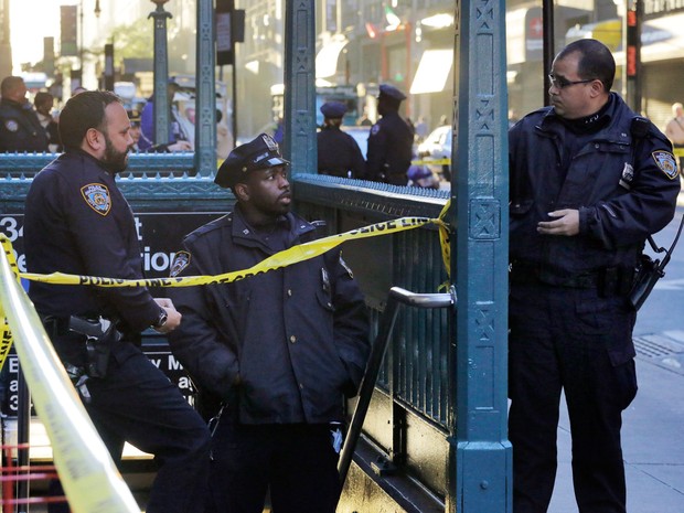 Policiais do Departamento de Polícia de Nova York investigam um tiroteio na estação de metrô da 35th rua com a oitava avenida em Nova York, EUA. Segundo as autoridades, três pessoas foram baleados e uma morreu. Nenhum suspeito foi preso  (Foto: Mark Lennihan/AP)