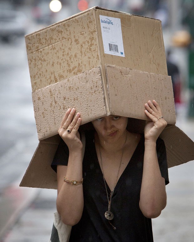 Uma mulher foi fotografada improvisando uma caixa para se proteger da chuva em Manhattan, em Nova York (EUA), na segunda-feira (22) (Foto: Carlo Allegri/Reuters)