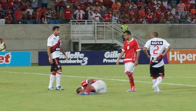 Isac (no chão), atacante do América-RN, após sofrer falta do goleiro Wilson, do Vitória (Foto: Augusto Gomes)