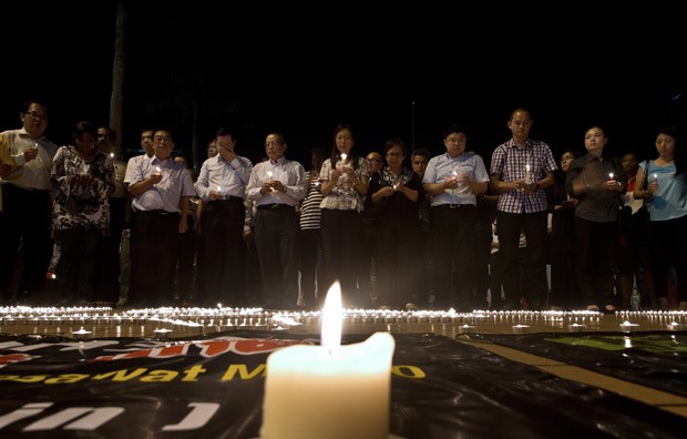 Famílias fazem orações durante vigília em praça de Kuala Lumpur (Foto: Manan Vatsyayana/AFP)