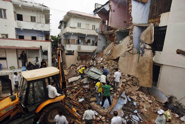 Equipes trabalham entre os escombros de prédio que ruiu nesta sexta-feira (26) na cidade indiana de Ahmedabad (Foto: Ajit Solanki/AP)