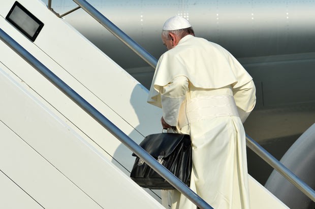 O Papa Francisco leva sua própria bagagem de mão ao embarcar para o Brasil, nesta segunda-feira (22), no aeroporto de Roma (Foto: Alberto Pizzoni/AFP)