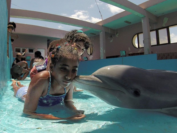  Garota Legna Fuentes é 'beijada' por golfinho Xinana  (Foto: AFP Photo/Adalberto Roque)