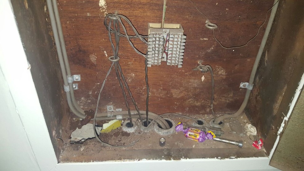 Parte elétrica das banheiras do motel, com fios desencapados e sem aterramento; há até papel de bombom dentro da caixa (Foto: Defesa Civil/Divulgação)