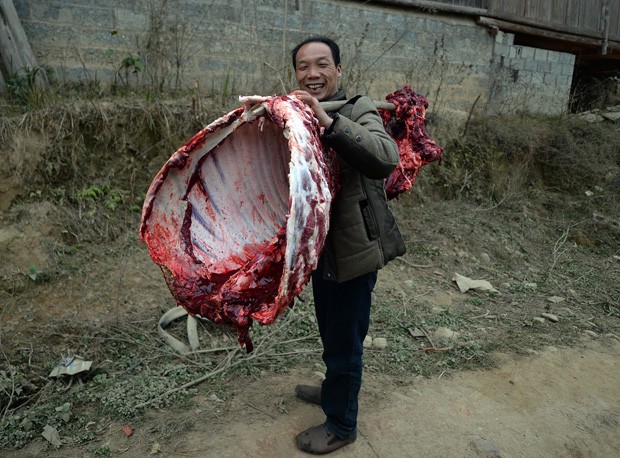 Homem sorri ao carregar 'banquete cru' para casa na China (Foto: Mark Ralston/AFP)