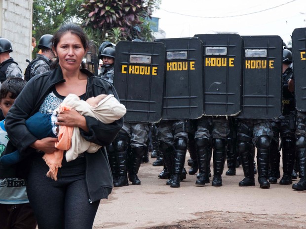 Mulher deixa o terreno com filho ao colo durante ação policial no Jardim Iguatemi (Foto: Peter Leone/Futura Press/Estadão Conteúdo)
