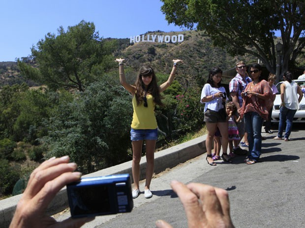 Pessoas fotografam placa de Holliwood em Los Angeles, do Griffith Park (Foto: Damian Dovarganes/AP Photo)