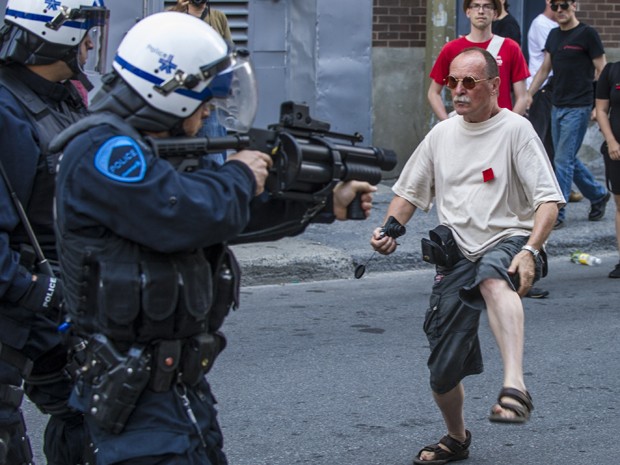 Homem enfrenta a polícia durante os protestos deste domingo (22) contra os altos custos da educação no Canadá (Foto: AFP/Rogerio Barbosa)