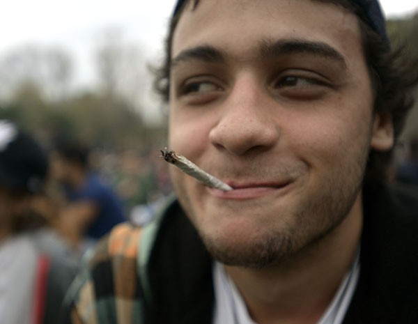 Jovem fuma um cigarro de maconha em parque de Montevidéu na marcha de comemoração. (Foto: Matilde Campodonico/AP)