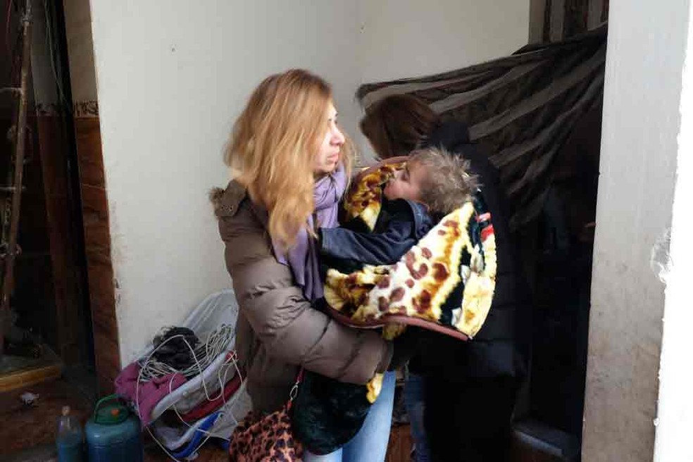 Funcionária de ONG carrega no colo o pequeno Yamen, de nove meses (Foto: Nicholson/Caritas)