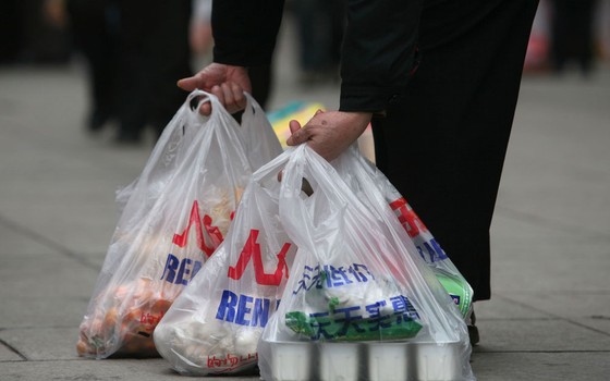 Consumidor carrega compras em sacolas plásticas em Pequim, China (Foto:  China Photos/Getty Images)