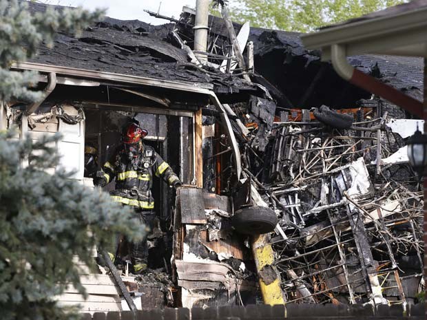 Bombeiro trabalha em escombros de uma casa no subúrbio de Denver, depois de apagar incêndio causado pela queda de um pequeno avião (Foto: AP/Brennan Linsley)