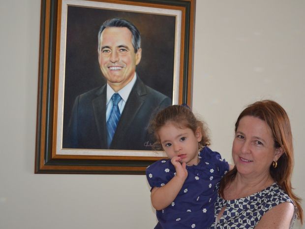 Simone e a neta Luiza ao lado do retrato de Pedrinho Valadares (Foto: Tássio Andrade/G1)