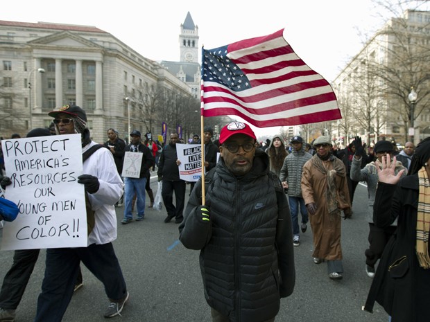 O diretor de cinema Spike Lee carrega uma bandeira dos EUA na Pennsylvania Avenue, perto do Capitólio, em Washington, durante protesto no sábado (13) (Foto: AP Photo/Jose Luis Magana)