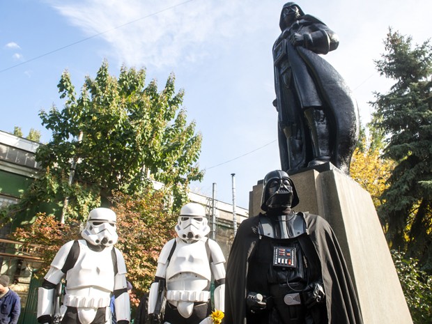 Pessoas vestidas como personagens de ‘Guerra das Estrelas’ posam ao lado de estátua de Darth Vader em Odessa, na Ucrânia, na sexta (23) (Foto: AFP Photo/Volodymyr Shuvayev)