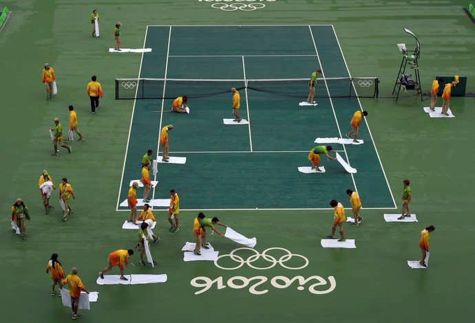 Voluntários secam a quadra central de tênis para iniciar as disputas do dia (Foto: REUTERS/Toby Melville)
